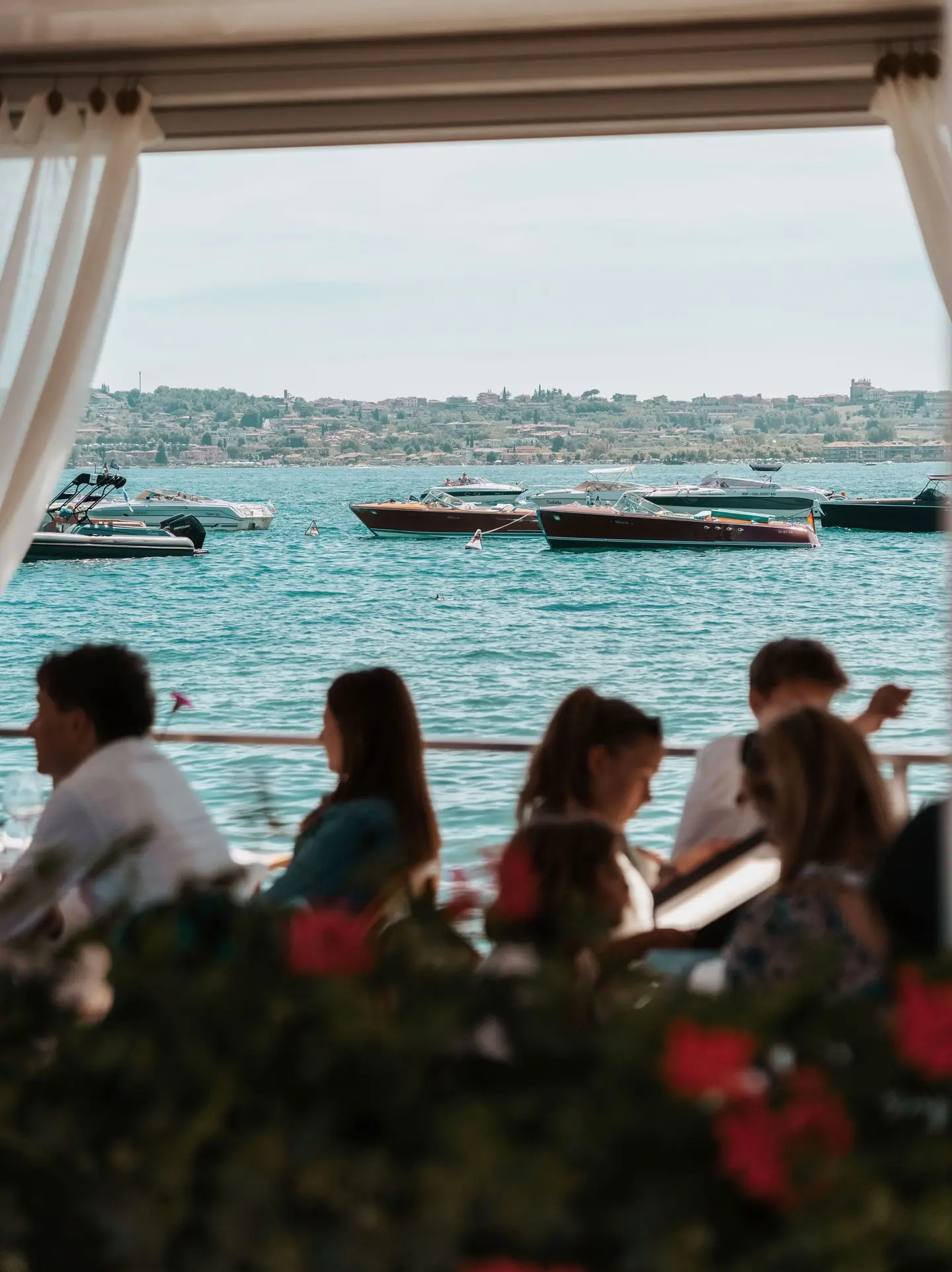 Ospiti a tavola sulla terrazza, con le barche sul lago
